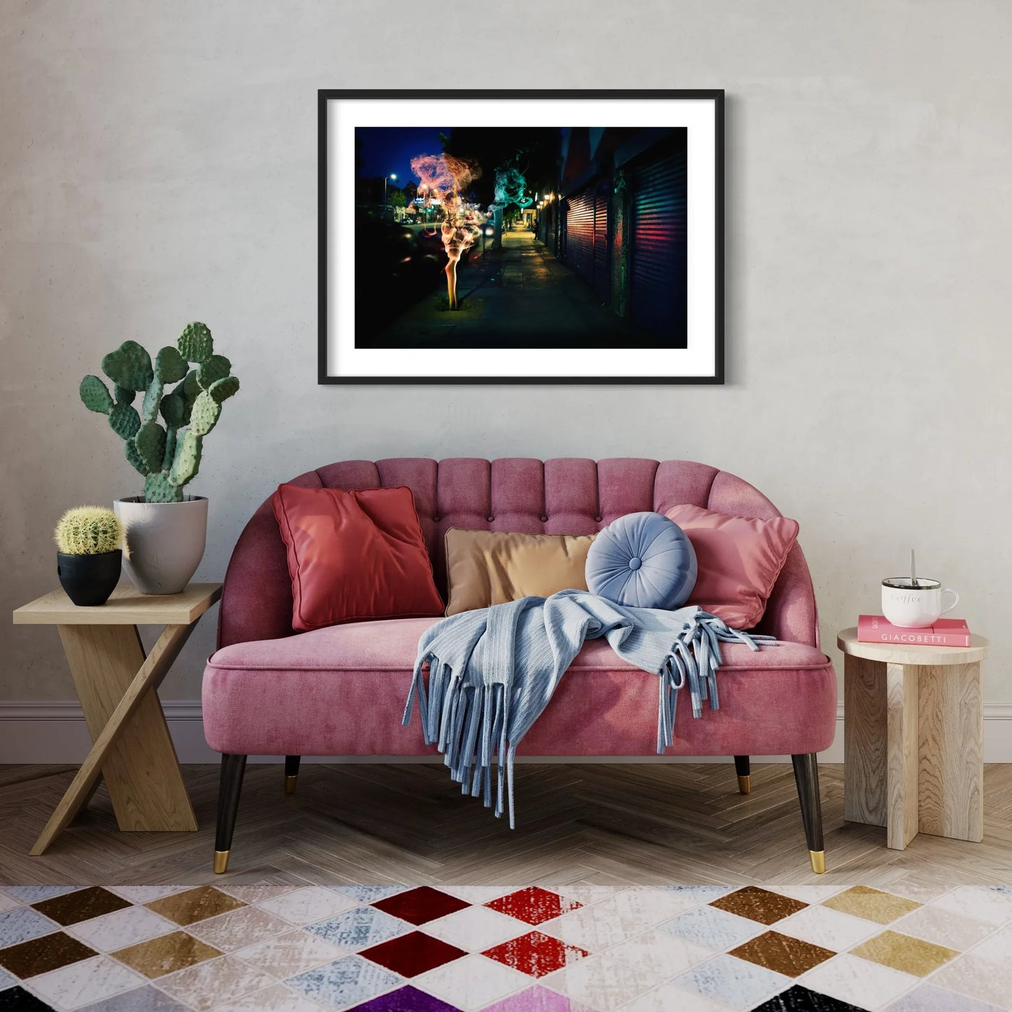 Pink sofa in a living room with a framed picture above it, plants on side tables, and a colorful rug.