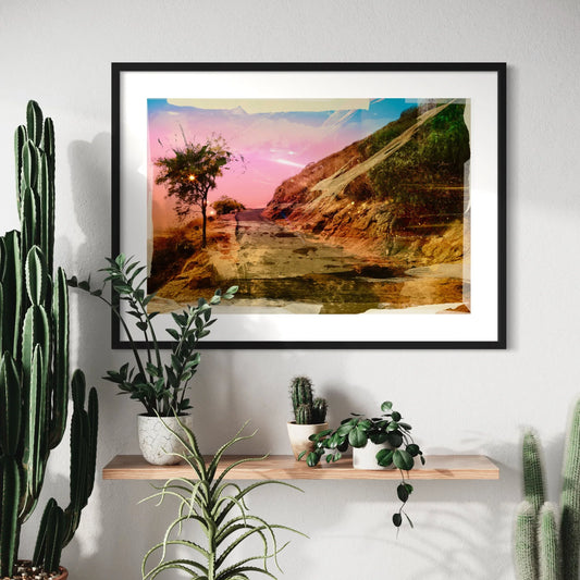 Framed landscape print on a wall with plants below