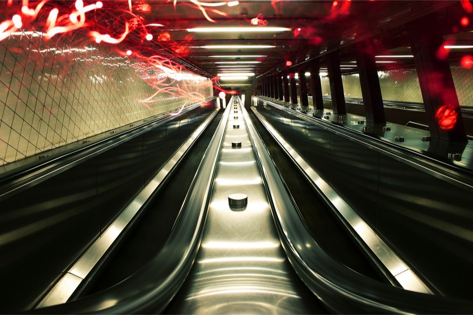 Industrial fine art photography of Manhattan subway escalators, steel and red light anomalies, symmetrical composition, cinematic underground aesthetic.