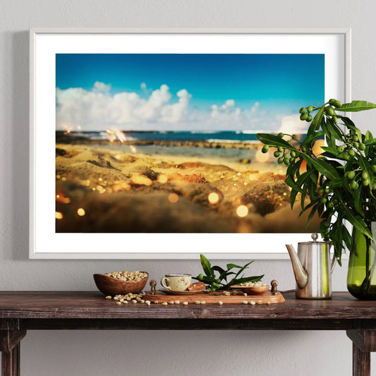 Framed beach scene on a wall above a wooden table with decorative items.